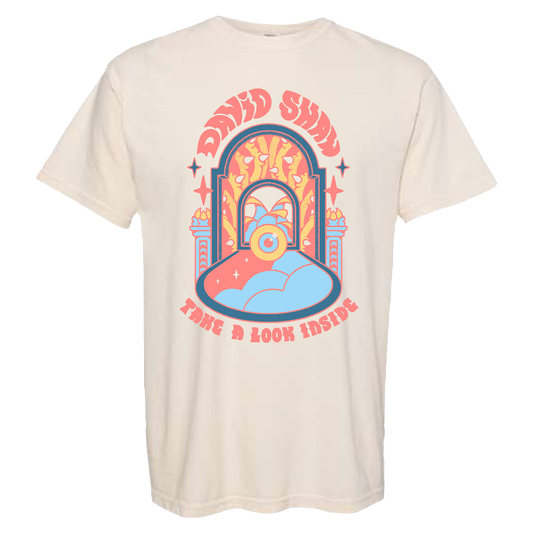 Cream-colored t-shirt with a colorful retro-style graphic design featuring the text ’DAVID SHRIGLEY’ and ’HAVE A GOOD THING’.